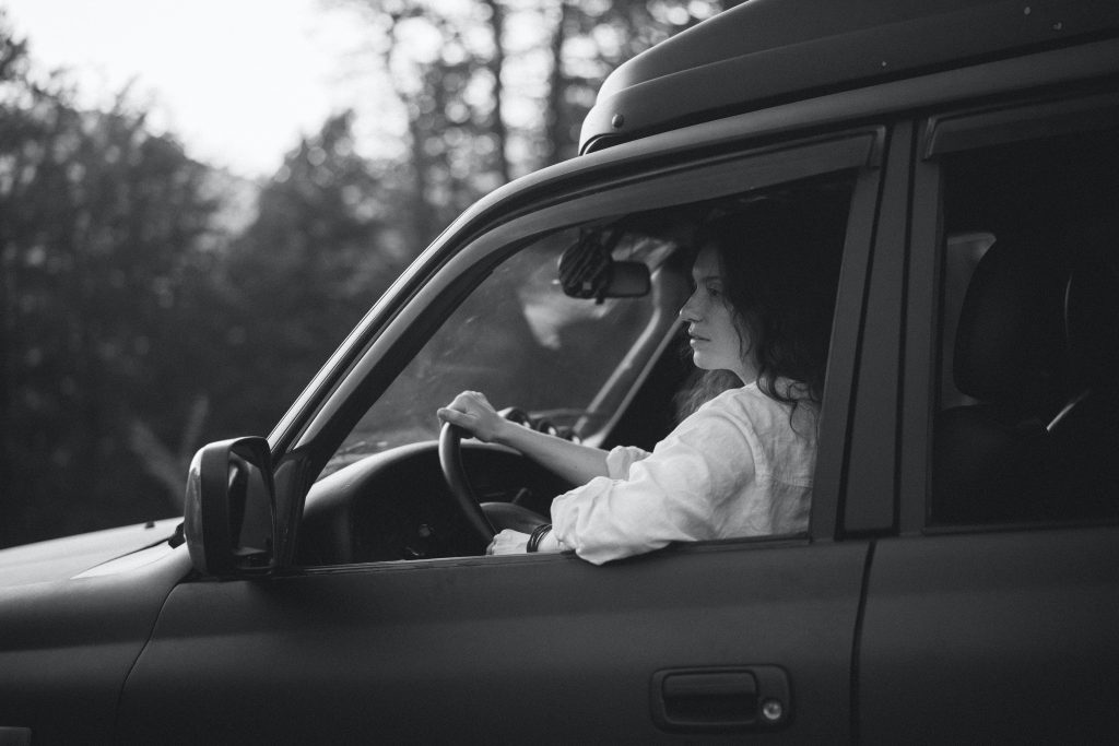 a greyscale photo of a woman in a 4x4 truck